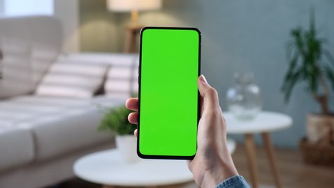Handheld Camera: Point of View of Woman at Phone with Green Screen for Copy Space. Chromakey 20s Lady Watching Video News on Couch Close up. Tap to Click on Centre of Screen