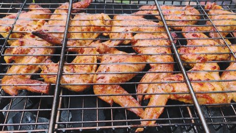 Chicken wings in sauce are grilled on a grill.