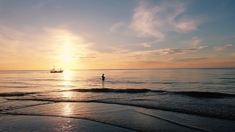 Slow motion Fisherman finding fish on tropical beach in the morning with boat and sunrise sky background at Hua Hin beach in Thailand.