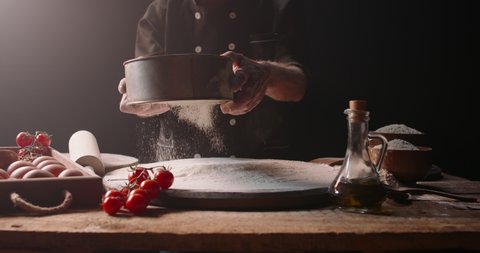 Closeup shot of experienced italian bakery chef sifting flour through sieve, starting to make pizza with traditional methods, isolated on black background 4k footage