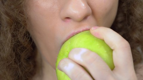 lips close up. beautiful woman bites a juicy green apple.