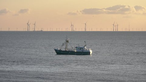 Fishing boat on the north see coast with wind turbines on the background