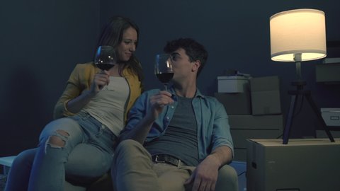 Happy couple toasting together with wine at night in their new house, home relocation and lifestyle concept – Stockvideo