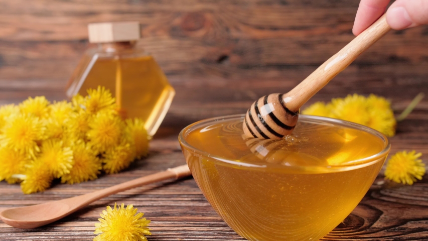 Bowl with dandelion honey and spoon on wooden table Royalty-Free Stock Footage #1054721954