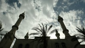 A large 4 tower Mosque silhouette with cloudy sky above. wide angle 4K video clip.