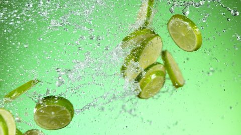 Super slow motion of lime pieces collision with water splashes, green background. Filmed on high speed cinema camera, 1000 fps.