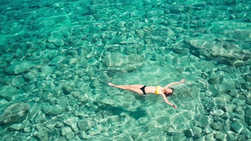 A woman swims in blue sea water in the bay. Nature and relaxation, top view. High quality 4k footage Royalty-Free Stock Footage #1054726202
