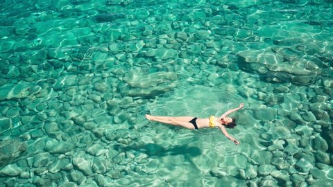 A woman swims in blue sea water in the bay. Nature and relaxation, top view. High quality 4k footage
