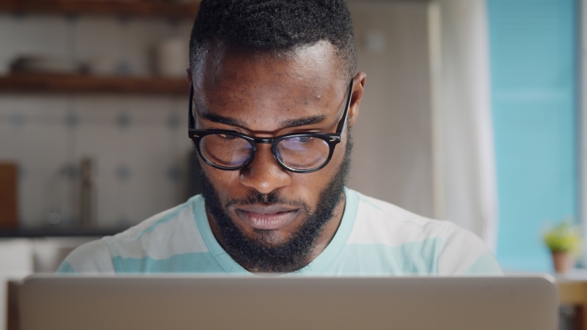 Young african freelancer man working on computer at home. Casual concentrated entrepreneur developing new project while working on laptop at home. | Shutterstock HD Video #1054726322
