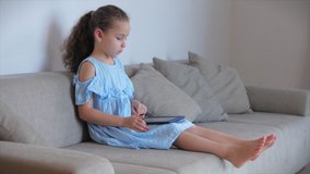 Happy Little Girl or child playing at home relaxing use a smartphone cuddling sit on sofa daughter and son,look at the screen of a cell phone, watch cartoons.