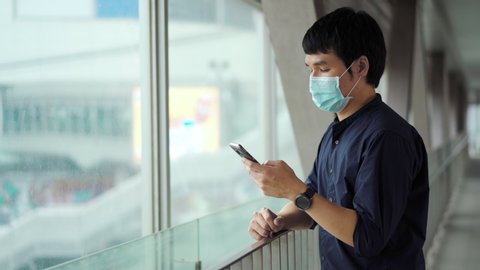 young asian man using smartphone and wearing medical mask for prevention from coronavirus (Covid-19) pandemic in the city. new normal concepts