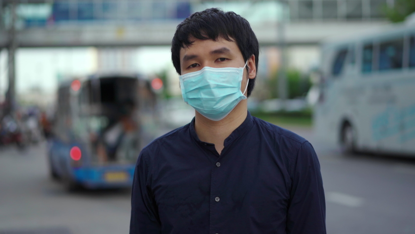 Young asian man wearing medical mask for prevention from coronavirus (Covid-19) pandemic on street in the city. new normal concepts | Shutterstock HD Video #1054726586