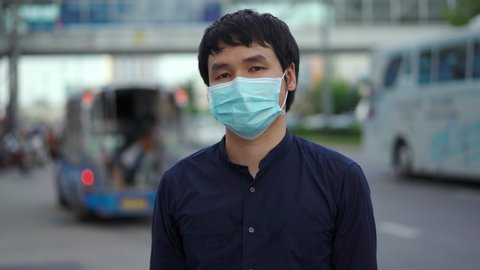 young asian man wearing medical mask for prevention from coronavirus (Covid-19) pandemic on street in the city. new normal concepts