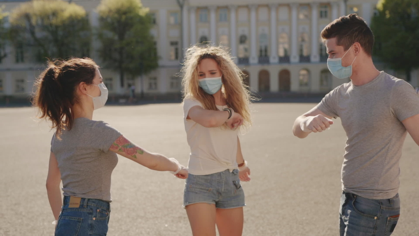 Social distancing. Multiracial Friends in protective face mask greet their elbows. Elbow bump is new greeting to avoid spread of coronavirus or covid-19 - Avoid or Stop handshakes due to pandemic | Shutterstock HD Video #1054726646
