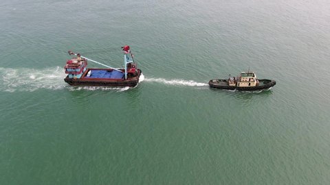 Tugboat pulling a small Barge in Hong Kong bay, Aerial view.