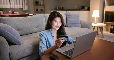 asian woman shopping on the internet and pay bill by credit card with laptop at home