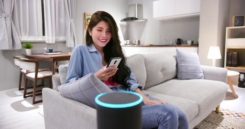 Smart AI speaker concept - asian young woman talk to voice assistant to control light turning off at home