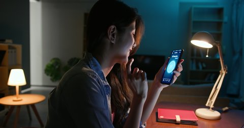 asian young woman using smart home app to control light turning on with mobile phone