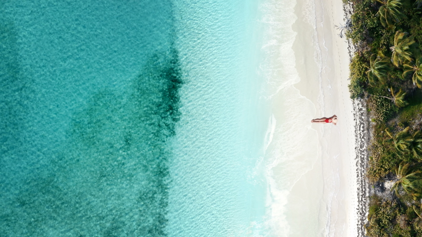 Girl lying on the beach aerial view. Young beautiful girl resting on white sand beach top view. Aerial view of the beautiful young lying woman near sea with waves at sunset. Summer holiday idyllic. | Shutterstock HD Video #1054729304