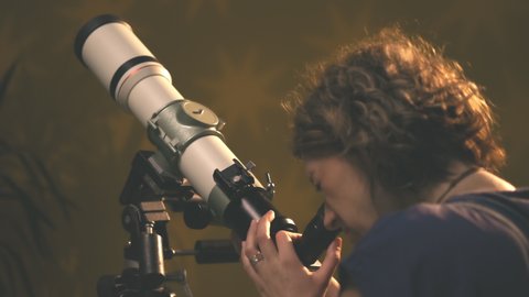 Woman looking at the stars through a telescope- astrology concept, horoscope predictions about the future.