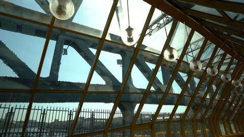 Empty long glass tunnel on the pedestrian bridge of yellow color with a panoramic glass roof . The camera is in motion. A bright Sunny day. close-up