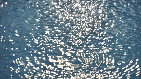 Circles on water. Summer rain, rainy season. Ripples, sun glare, circles on waves water. Sea ripples. Sun Blurry glare on blue turquoise water. Blurry water background, relax. Slow motion video.