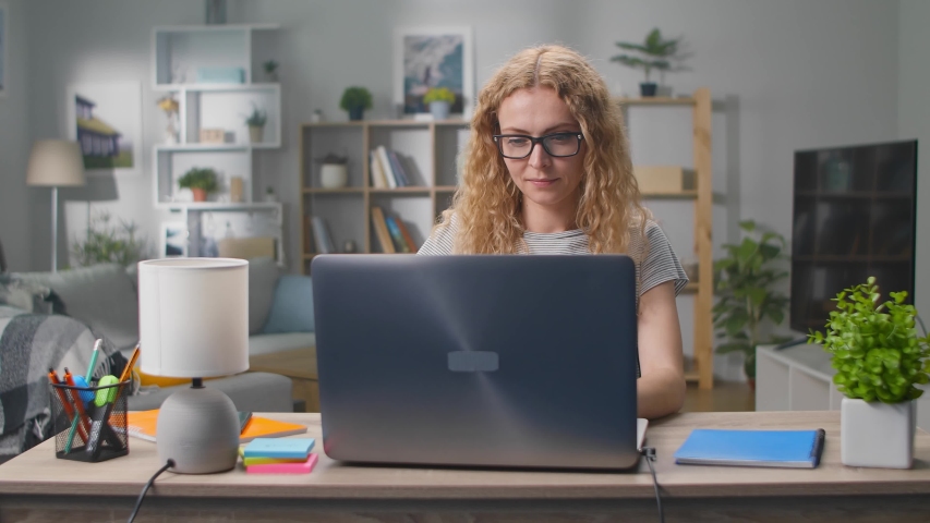 Young woman looking on the Internet while sitting with a laptop in her living room Royalty-Free Stock Footage #1054730438