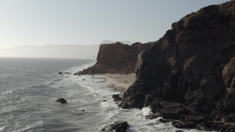 Aerial orbit shot of waves washing up on the Point Dume beach in Malibu sunset