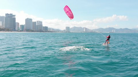 Aerial view of the city beach and active people practicing kite surfing and windsurfing. Kitesurfing place, sports concept, healthy lifestyle, human flight.