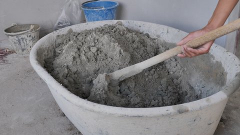 professional construction worker mixes wet grey cement slow motion close
