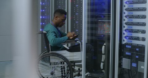 Medium shot of a wheelchaired technician working in data center