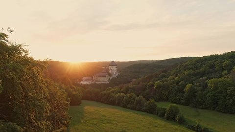 Panoramic aerial drone view of famous Karlstejn castle, Czech Republic. Castle in beautiful forest is built in gothic style. Founded by king and emperor Charles IV. Sunset time, warm colors. 