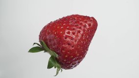 Macro video of an red strawberry, rotating white background