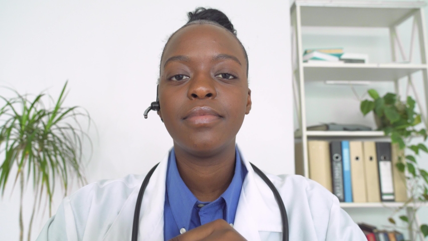African female doctor wear headset make online video call consult patient. Afro american black woman therapist videoconferencing talking to camera in remote chat. Telemedicine, telehealth. Webcam view Royalty-Free Stock Footage #1054741856