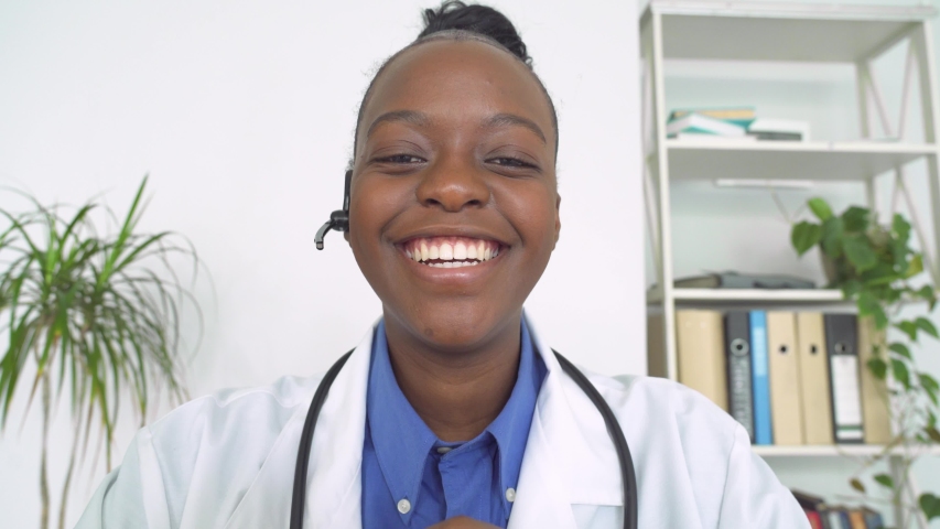 African female doctor wear headset make online video call consult patient. Afro american black woman therapist videoconferencing talking to camera in remote chat. Telemedicine, telehealth. Webcam view | Shutterstock HD Video #1054741856