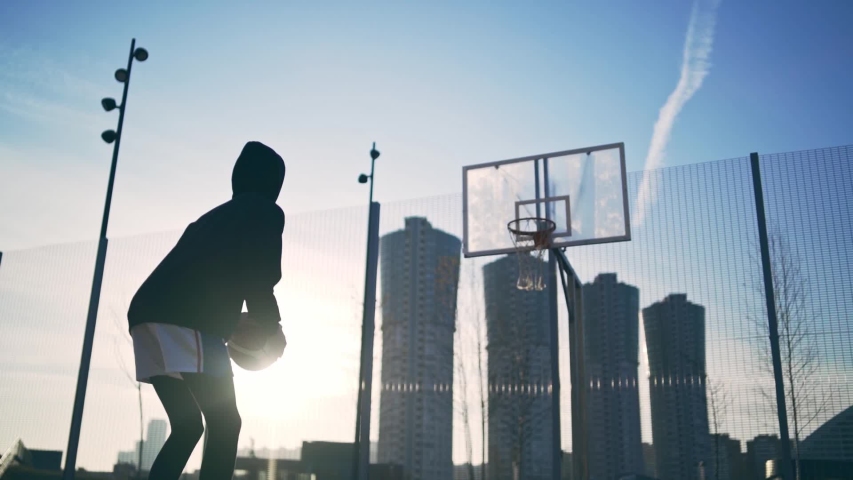 Back view of unrecognizable player throwing ball in a basketball hoop, the ball hits the ring and scores. Slowmotion shot Royalty-Free Stock Footage #1054744151