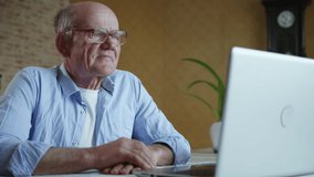 doctor online, an elderly attractive old man with glasses for eyesight consults with a therapist using modern technologies, shows him medications while sitting at a laptop at a table