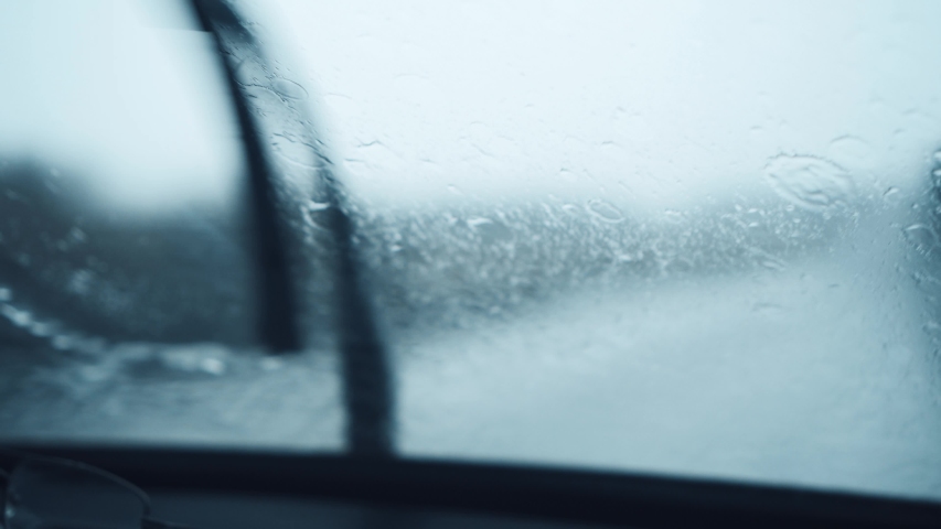 Front car windshield with rain drops on it while driving. Focusing rain drops. Driving in the rain. Royalty-Free Stock Footage #1054746599