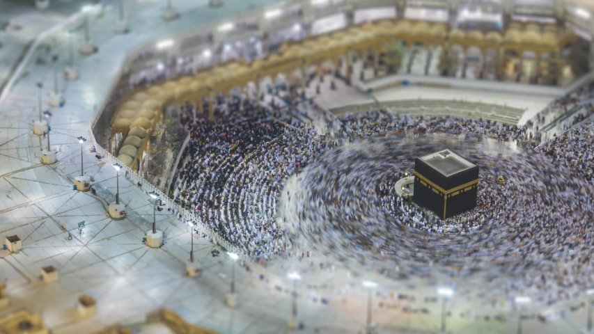 Tilt shift Time lapse sunrise of Muslim pilgrims circling around the holy Kaaba at dawn and praying inside al Masjid al Haram in Mecca, Saudi Arabia. Zoom out motion timelapse. Prores UHD Royalty-Free Stock Footage #1054751255