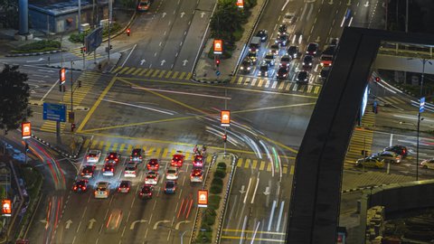 KUALA LUMPUR, MALAYSIA  - NOVEMBER 02, 2019 : Time lapse : High angle night shot of a busy city traffic light intersection with cars light trails in Malaysia. Zoom out motion timelapse. Prores Full HD