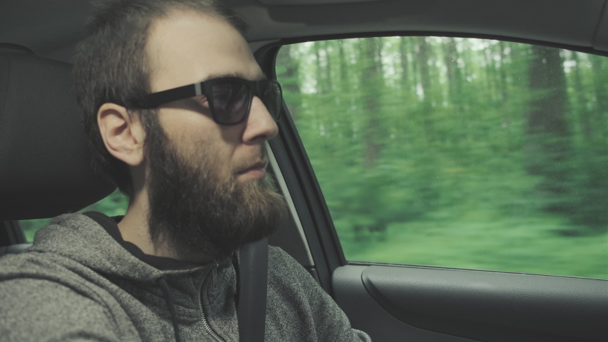 Young man drives a car through the woods.