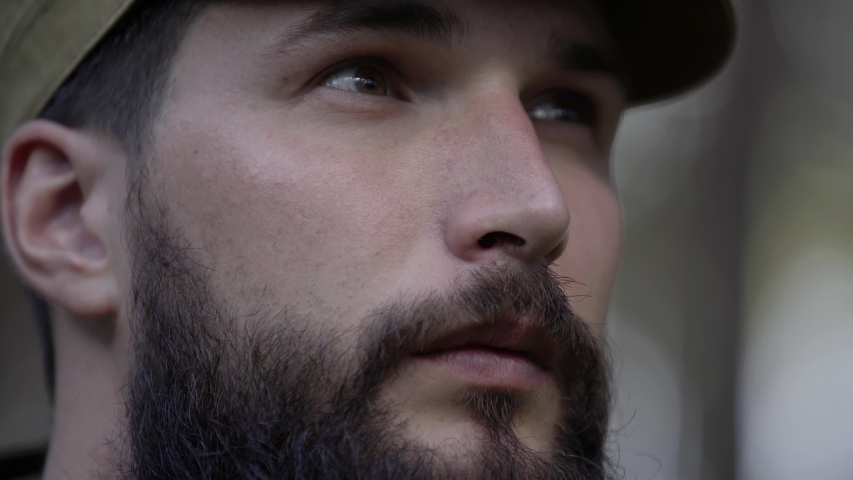 Portrait of handsome young man hunter or tourist. Man in camouflage clothes hunts outdoor in forest hunting alone. Close up of man hiker standing in forest. Hunter hunts down prey