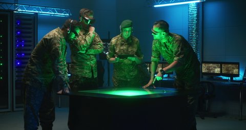 Medium shot of VR headset wearing modern soldiers discussing military strategy using holographic technology for emulation and modulation of tactic situations during battle, futuristic concept.