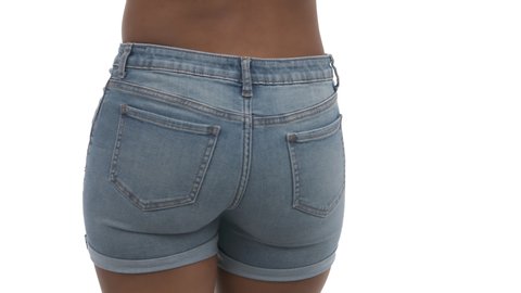 African model wearing tight light blue denim shorts posing to camera and moving hips. Isolated on white.