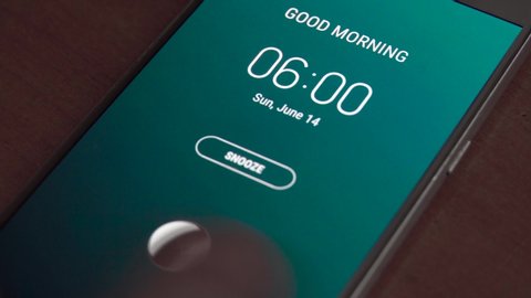 Good morning 6 am alarm clock on the phone, a finger taps snooze.