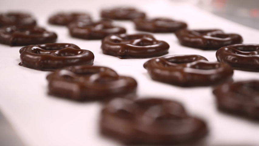 Close up footage of chocolate covered pretzels drying after coming out from the chocolate enrober