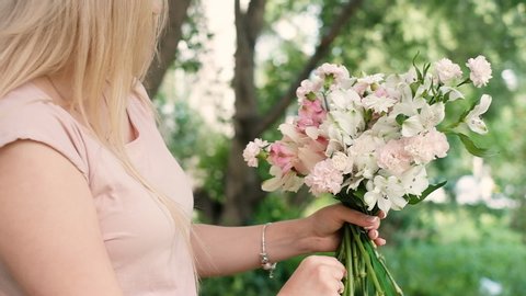 Стоковое видео: beautiful woman florist collects a magnificent bouquet of flowers for the holiday. She puts flowers out of a vase florist tools. Business concept. Shop. 20-25 years. outdoor work