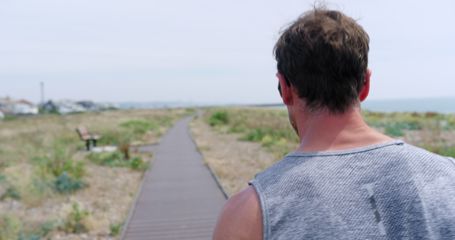 MS SLO MO TS Mature man jogging on boardwalk at seaside / Sussex, UK