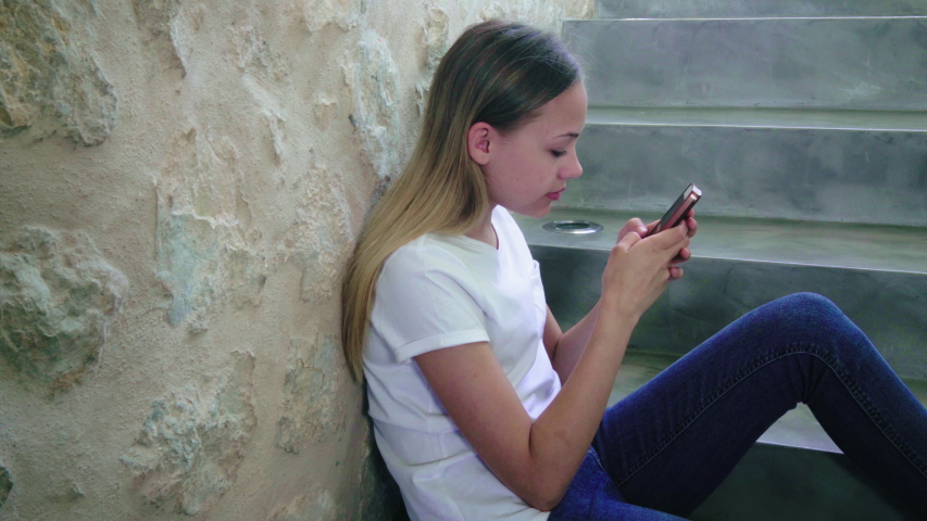 MS Girl (12-13) sitting on stairs and using smart phone, Holidays, People