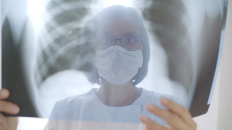 Female doctor checking patient's chest x-ray film lungs scans at radiology department in hospital. Lung disorders or Covid-19 scan lungs xray detection. Covid  virus epidemic spread concept 4K video.